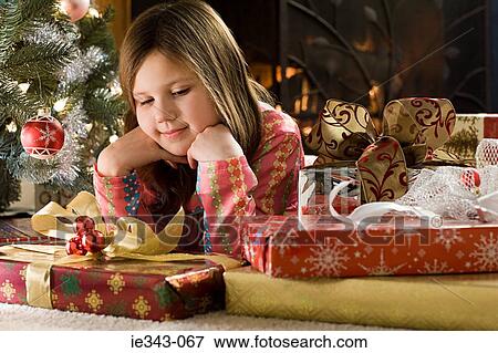 Stock Photo - Girl looking at christmas gifts. Fotosearch