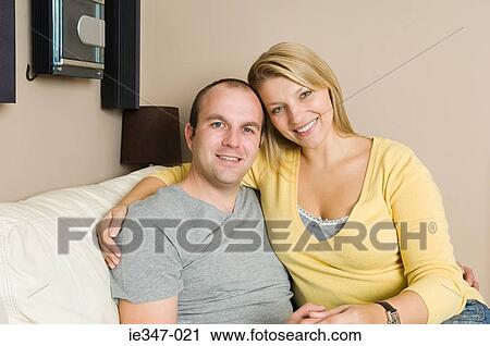 Couple sitting on sofa View Large Photo Image Stock Image - Couple sitting on sofa. Fotosearch
