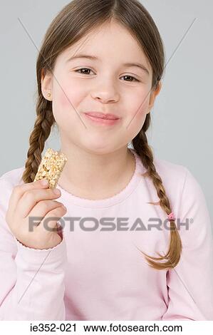 Girl eating cereal bar View Large Photo Image Stock Image - Girl eating cereal bar. Fotosearch