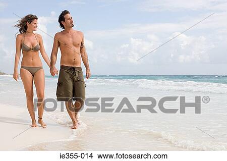 A couple walking along a beach View Large Photo Image Picture - A couple walking along a beach. Fotosearch