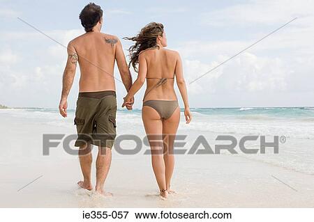 Stock Photo - A couple walking along a beach. Fotosearch