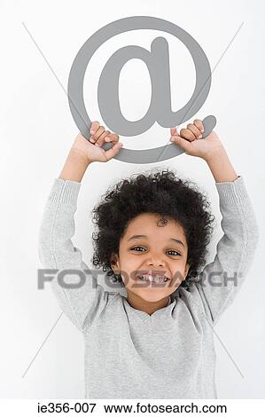 Boy holding an at symbol View Large Photo Image Stock Photo - Boy holding an at symbol. Fotosearch