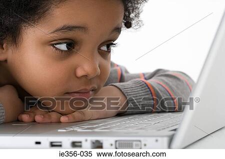 Stock Photography - Boy leaning on laptop. Fotosearch