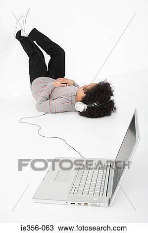 Stock Image - Boy listening to music on laptop. Fotosearch