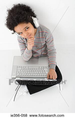 Stock Photo - Boy listening to music on laptop. Fotosearch