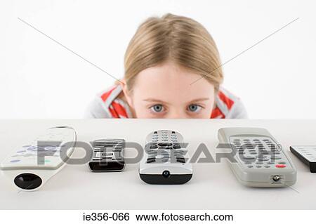 Girl looking at remote controls View Large Photo Image Stock Photograph - Girl looking at remote controls. Fotosearch