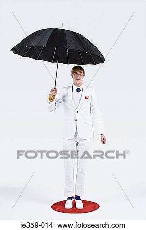 Picture - A businessman holding an umbrella. Fotosearch