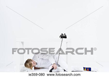 A businessman lying under a desk View Large Photo Image Stock Image - A businessman lying under a desk. Fotosearch