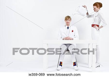 A businesswoman holding a watering can over a businessman View Large Photo Image Stock Photo - A businesswoman holding a watering can over a businessman. Fotosearch