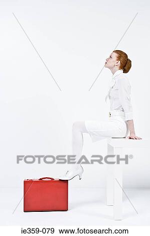 Stock Photo - A businesswoman sitting on a desk. Fotosearch