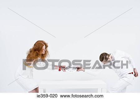 Stock Image - A man and woman fighting over a clock. Fotosearch