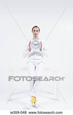 Stock Photo - A man holding a clock. Fotosearch