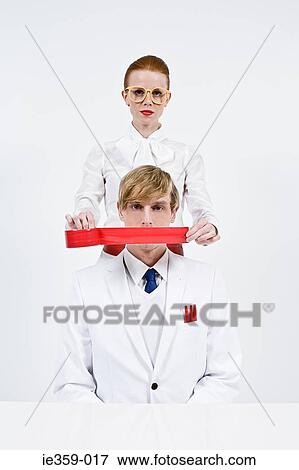 A woman covering a mans mouth with red tape View Large Photo Image Stock Photo - A woman covering a mans mouth with red tape. Fotosearch
