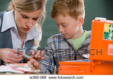 Teacher and boy with plaster on finger View Large Photo Image Stock Photo - Teacher and boy with plaster on finger. Fotosearch