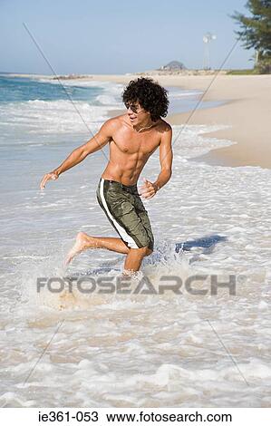 Stock Image - A teenage boy running in the sea. Fotosearch
