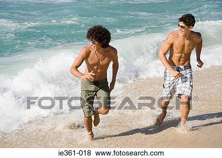 Stock Photo - Teenage boys running on the beach. Fotosearch