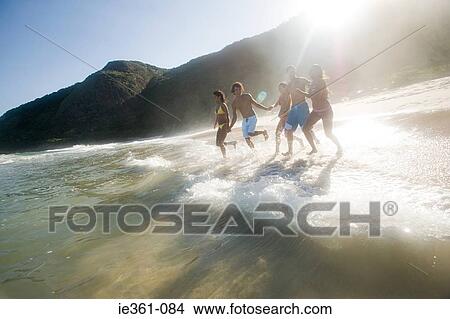 Picture - Teenagers running into the sea. Fotosearch
