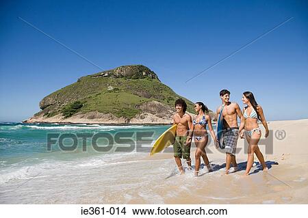 Picture - Teenagers walking along a beach. Fotosearch
