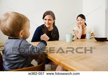 A baby boy and women sat at a table View Large Photo Image Stock Photo - A baby boy and women sat at a table. Fotosearch