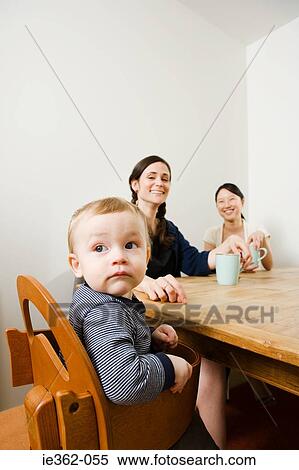 Stock Photography - A baby boy and women sat at a table. Fotosearch