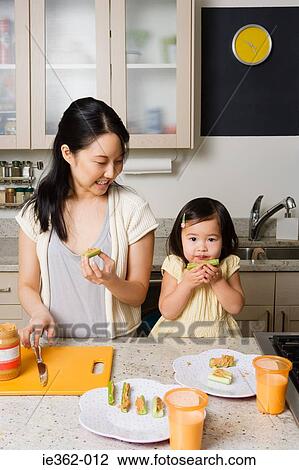 Stock Image - A daughter helping her mother in the kitchen. Fotosearch