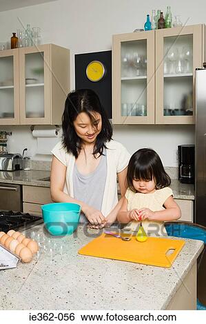 Stock Photograph - A daughter helping her mother in the kitchen. Fotosearch