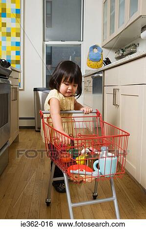 A girl pushing a toy trolley View Large Photo Image Stock Photograph - A girl pushing a toy trolley. Fotosearch