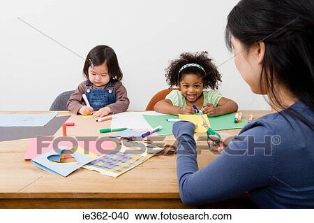 Stock Image - A woman supervising girls drawing. Fotosearch
