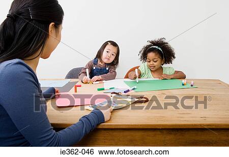 Stock Photograph - A woman supervising girls drawing. Fotosearch