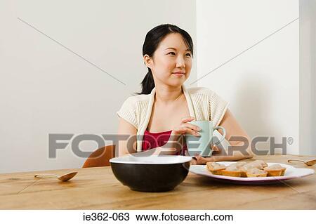 Stock Image - A young woman holding a coffee cup. Fotosearch