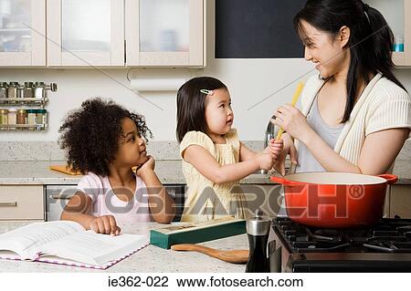 Stock Image - Children helping a woman cook. Fotosearch