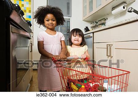 Girls pushing a toy shopping trolley View Large Photo Image Picture - Girls pushing a toy shopping trolley. Fotosearch