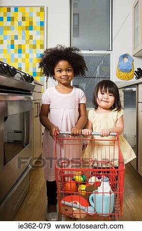 Girls pushing a toy shopping trolley View Large Photo Image Stock Photo - Girls pushing a toy shopping trolley. Fotosearch