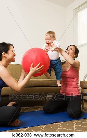 Two women playing with a baby boy View Large Photo Image Stock Image - Two women playing with a baby boy. Fotosearch