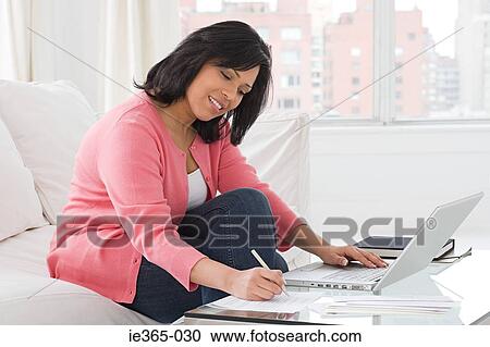 A woman using a laptop and writing View Large Photo Image Stock Image - A woman using a laptop and writing. Fotosearch