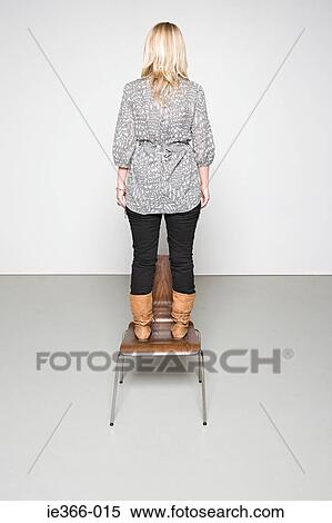 Woman standing on a chair View Large Photo Image Stock Photography - Woman standing on a chair. Fotosearch