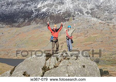A couple with raised arms on rocks View Large Photo Image Stock Photo - A couple with raised arms on rocks. Fotosearch