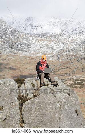 A man using a laptop on a rock View Large Photo Image Stock Photograph - A man using a laptop on a rock. Fotosearch
