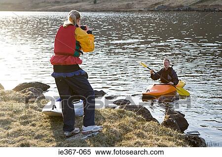 A woman photographing a man in a canoe View Large Photo Image Stock Photography - A woman photographing a man in a canoe. Fotosearch