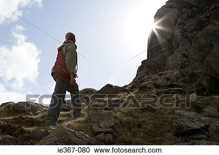 Stock Image - A young woman looking up at rocks. Fotosearch