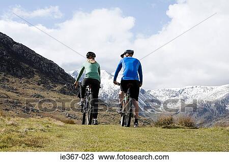 Rea view of a couple cycling View Large Photo Image Stock Image - Rea view of a couple cycling. Fotosearch
