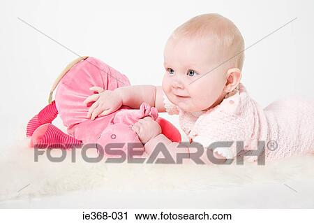 Stock Image - Baby girl holding a toy. Fotosearch