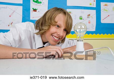 Boy looking at lightbulb View Large Photo Image Stock Photo - Boy looking at lightbulb. Fotosearch