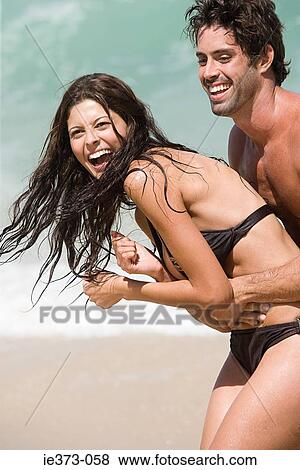 Stock Photo - Hispanic couple playing on a beach. Fotosearch