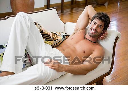Smiling man relaxing on a sofa View Large Photo Image Stock Image - Smiling man relaxing on a sofa. Fotosearch
