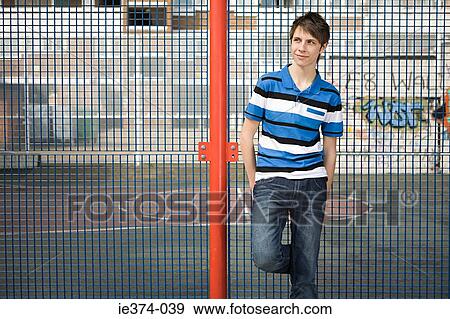 Stock Photo - Teenage boy leaning on fence. Fotosearch
