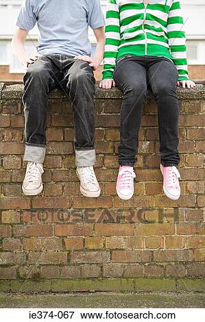 Stock Photo - Teenagers sitting on wall. Fotosearch