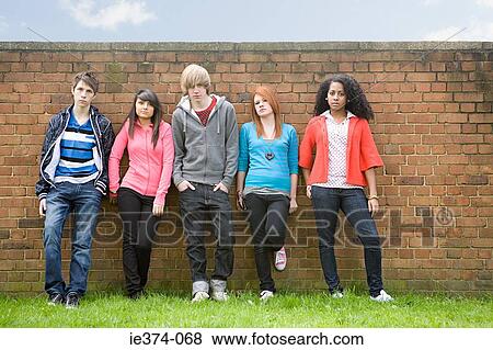 Teens standing by wall View Large Photo Image Stock Photo - Teens standing by wall. Fotosearch