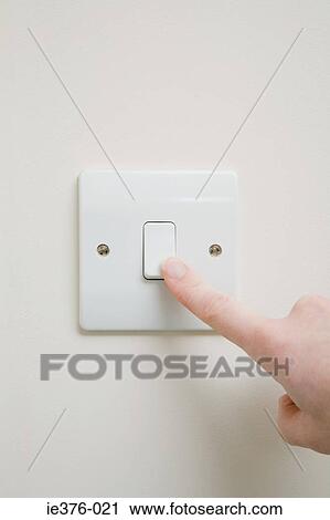 Stock Image - Person using light switch. Fotosearch