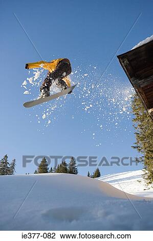 A snowboarder jumping off a cabin roof View Large Photo Image Stock Image - A snowboarder jumping off a cabin roof. Fotosearch